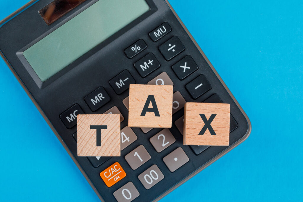 tax-planning-concept-with-wooden-cubes-calculator-blue-table-flat-lay-scaled.jpg